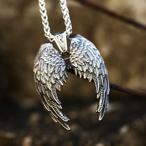 Close-up of vintage angel wing pendant with detailed feathers and braided chain