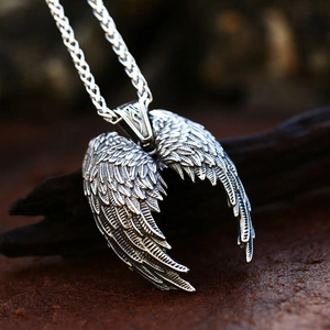 Close-up of vintage stainless steel angel wing pendant with detailed feather texture