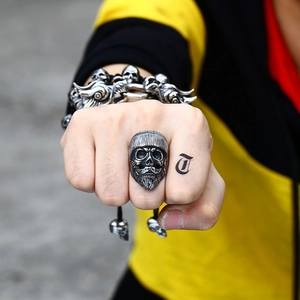Detailed close-up of a vintage stainless steel skull ring with a beard on a hand
