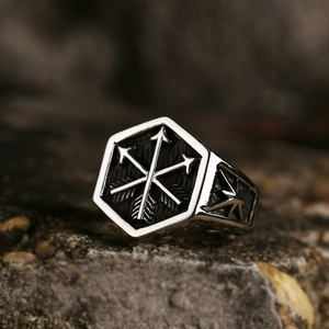 Macro shot of retro stainless steel ring featuring engraved triple arrows on a rocky texture