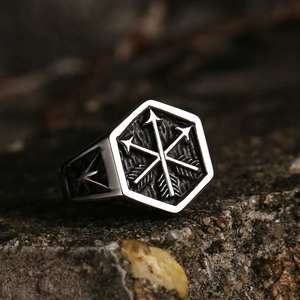 Vintage stainless steel signet ring with crossed arrows on a textured stone surface