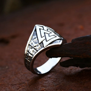 Vintage stainless steel Viking Valknut ring with Norse runes on a rustic wood background