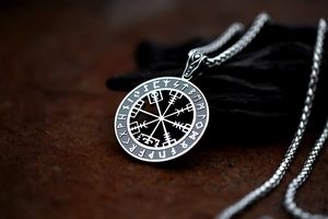 Macro-opname van zilveren Viking Vegvisir kompas hanger met runen op lederen ondergrond