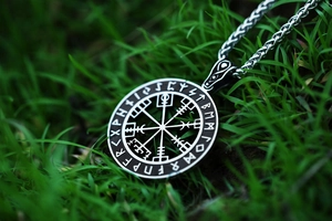 Macro detail van de Noordse Viking Vegvisir kompas hanger met runen op gras achtergrond