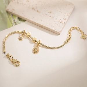 Détail du bracelet plaqué or avec médaille de la Vierge Marie et breloques étoile
