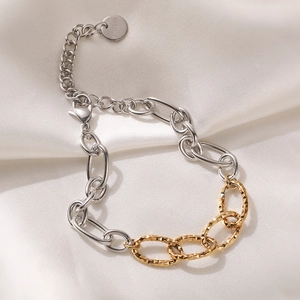 Two-tone 18K gold plated stainless steel heart chain bracelet on white silk fabric
