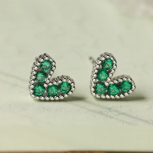Dettaglio di orecchini a cuore in argento con pietre di zirconia verde smeraldo