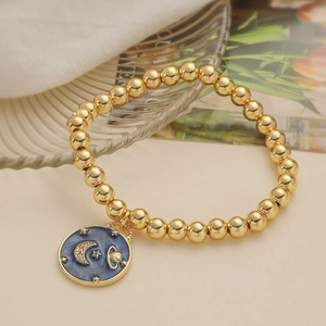 Golden bead stretch bracelet featuring a blue enamel sun and moon celestial charm