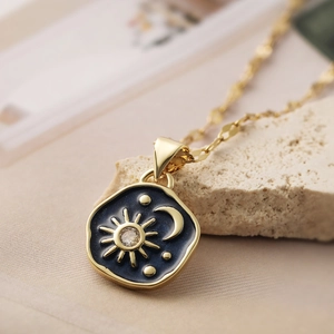 Detailed close-up of a vintage sun and moon pendant with blue enamel on a gold necklace
