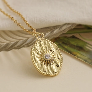 Retro 18K gold plated necklace with oval zircon sunburst pendant on a glass plate