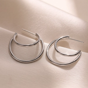 Boucles d'oreilles créoles doubles argentées minimalistes sur fond de soie champagne