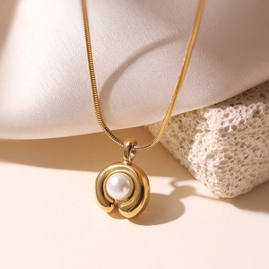 Minimalistische 18K vergoldete Schlangenkette mit Perlenanhänger auf Seidenstoff Hintergrund