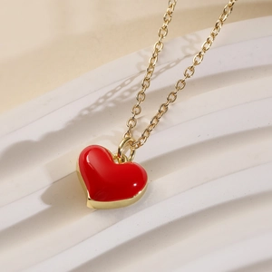 Elegant 18K gold plated copper necklace with red enamel heart pendant on white pedestal