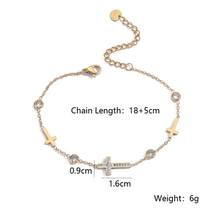 Dettaglio di un bracciale a croce in acciaio dorato con zirconi e chiusura a moschettone
