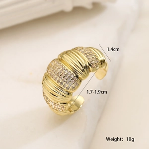 Détail macro d'une bague large plaquée or 18 carats avec zircons et design ondulé