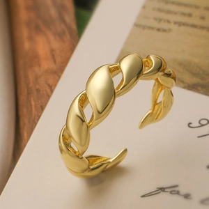 Détail d'une bague ouverte plaquée or 18 carats avec texture tressée sur un fond décoratif doux