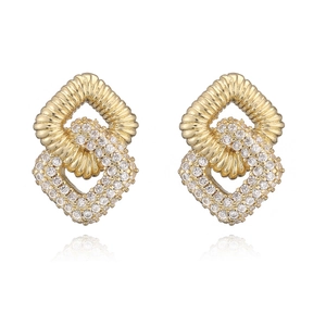 Macro shot of gold-plated geometric earrings featuring sparkling zircon stone settings