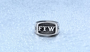 Macro shot of stainless steel biker ring with embossed FTW lettering on honeycomb pattern