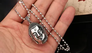 Détail du pendentif tête de Bouddha en argent vintage tenu en main pour comparaison