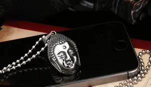 Gros plan d'un pendentif tête de Bouddha vintage en acier inoxydable argenté poli