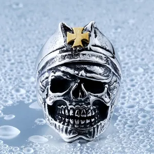 Vintage punk men's stainless steel skull ring with golden cross on a water droplet surface