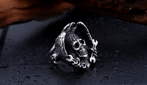 Detailed view of punk skull ring with eagle wings and wrenches on dark textured background