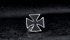 Macro shot of stainless steel biker ring with black drip oil Iron Cross on leather