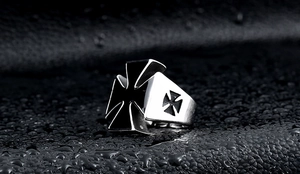 Macro shot of stainless steel iron cross ring for men on a wet textured surface