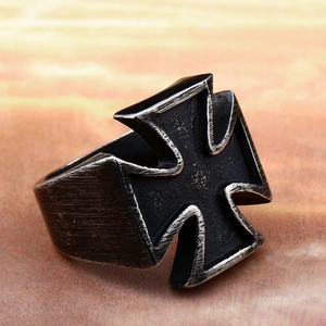 Close-up of vintage stainless steel iron cross ring with black finish and aged metal texture