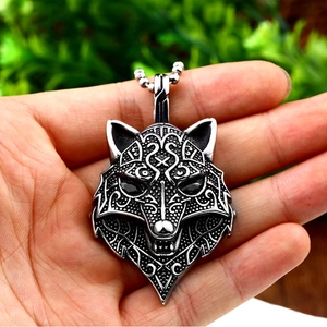 Close-up of vintage silver viking wolf head pendant with intricate celtic carvings and black gems