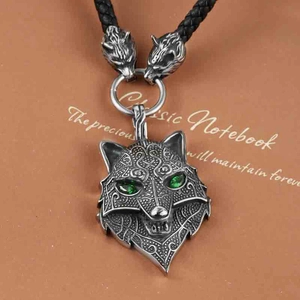 Detail of Viking wolf head pendant with green gem eyes and black braided cord