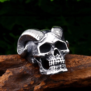 Anello gotico in acciaio inossidabile con teschio di ariete e corna su sfondo di legno