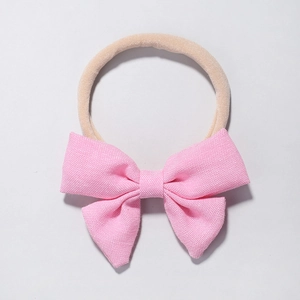 Pink bow headband for infants featuring soft fabric and nude elastic nylon band