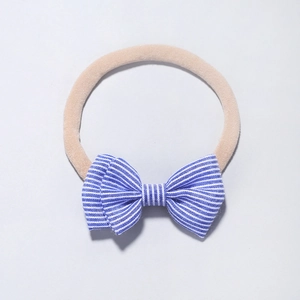 Détail d'un bandeau pour bébé en nylon avec un nœud en coton à rayures bleues sur blanc