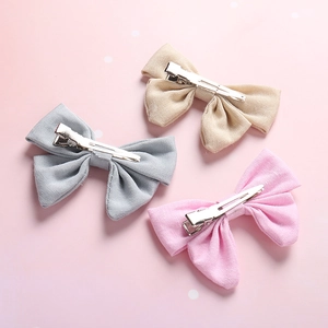 Three linen bow hair clips in beige, grey, and pink with silver alligator metal clips