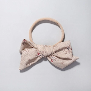 Detail of floral baby headband with a cream-colored bow and elastic nylon strap