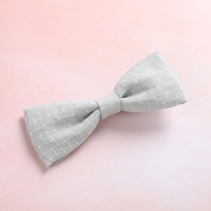Close-up of grey fabric hair bow with star patterns on soft pink background