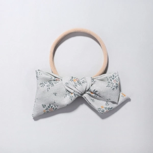Detailed close-up of floral print fabric bow on a soft nude nylon baby headband