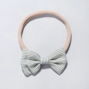 Détail d'un bandeau en nylon pour bébé avec un nœud à rayures vertes et blanches en coton