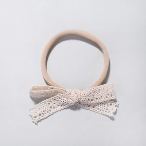 Detailed view of soft beige nylon headband featuring a delicate lace butterfly bow knot