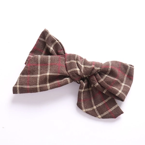 Detail of handmade cotton linen hair clip featuring brown and red plaid bow pattern