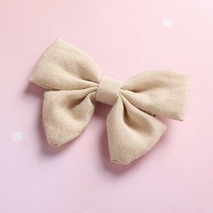 Close-up of beige linen cotton bow hair clip with textured fabric for girls