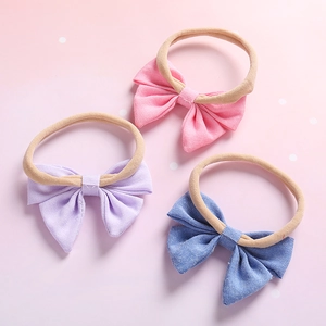 Trois bandeaux bébé en nylon souple avec nœuds en tissu rose, lilas et bleu