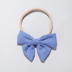 Detail of blue textured woven bow baby headband with highly elastic nylon band in nude color