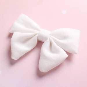 Detailed macro view of white linen bow hair clip with visible woven fabric texture