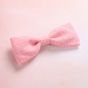 Close-up of pink cotton fabric bow hair clip with white star patterns and natural texture