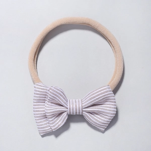 Détail d'un bandeau en nylon pour bébé avec un nœud rayé de couleur café et blanc