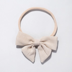 Detail of baby headband featuring textured oatmeal fabric bow on soft nylon elastic band