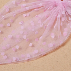 Vue rapprochée du tissu en tulle rose avec des cœurs floqués et texture fine