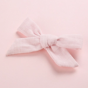 Detailed close-up of pink cotton fabric hair clip showing natural woven texture and bow